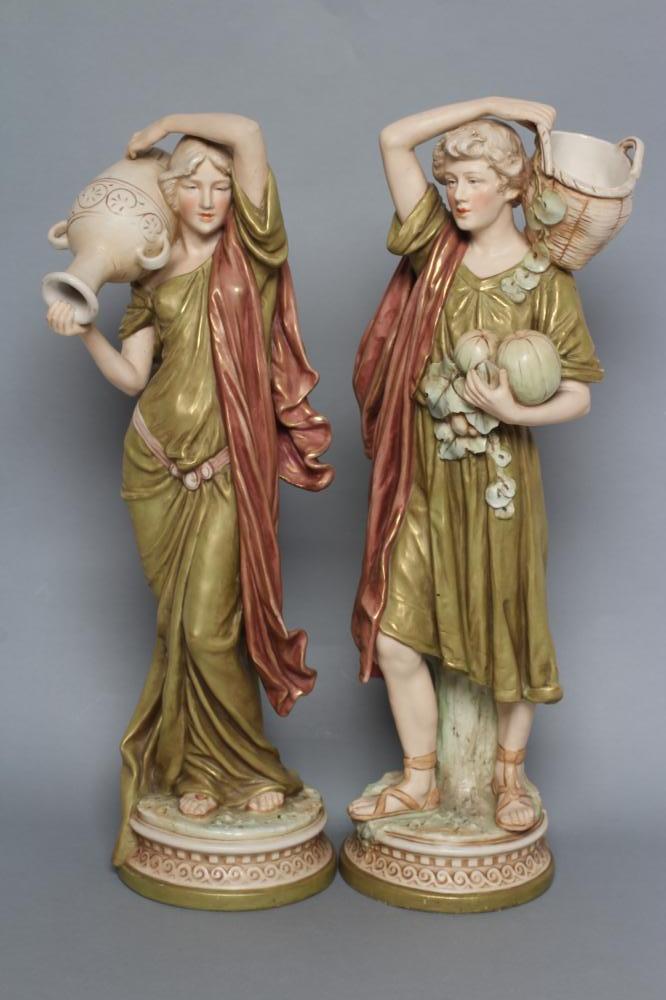 A PAIR OF ROYAL DUX PORCELAIN FIGURES, early 20th century, modelled as a young man holding a