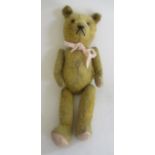 A pre-war teddy, c. 1920, with amber eyes, sewn nose, orange plush, jointed body, pink felt pads and