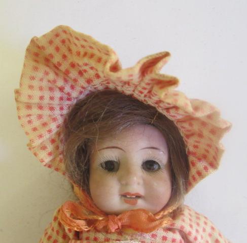 An all bisque miniature mignonette dolls house doll, with brown glass fixed eyes, open mouth, teeth,