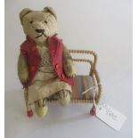 A 6 1/2" teddy, with sewn eyes and nose, jointed body, red felt jacket, fabric skirt and vintage