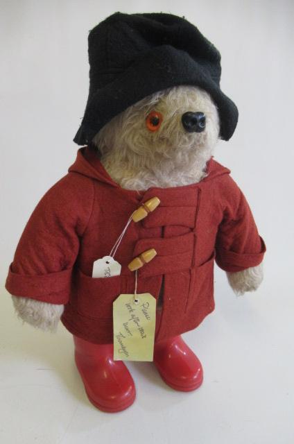 A Paddington bear, with red coat, red wellies and label