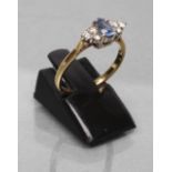 A THREE STONE SAPPHIRE AND DIAMOND RING, the central oval facet cut stone claw set and flanked by
