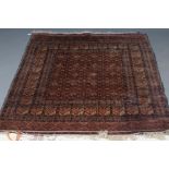 AN AFGHAN RUG in muted shades of red, camel, pale green and ivory, the field with a repeating flower