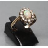 AN OPAL AND DIAMOND CLUSTER RING, the oval cabochon polished opal claw set to a border of small