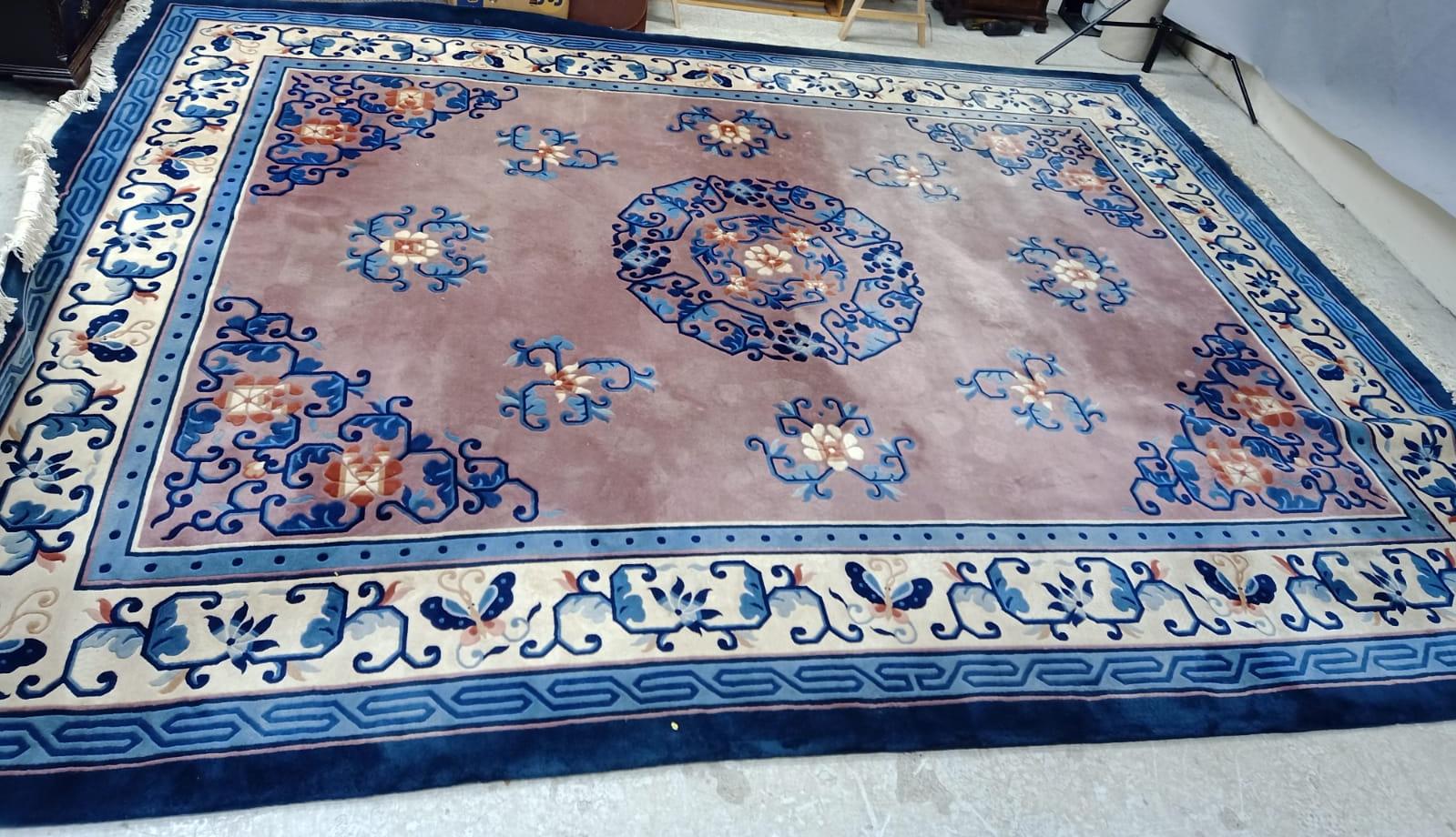 A CHINESE WASHED AND FRINGED CARPET, the dusky pink field with central floral gul in shades of blue,