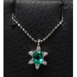 AN EMERALD AND DIAMOND PENDANT, the oval facet cut emerald claw set to an open border of six small