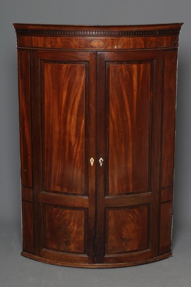 A GEORGIAN MAHOGANY CORNER CUPBOARD, c. 1800, of bowed form with rosewood banding and stringing,