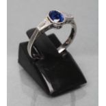 A CEYLON SAPPHIRE AND DIAMOND RING, the oval facet cut sapphire of 1.26cts collet set to angular