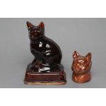 AN ENGLISH TREACLE GLAZED STONEWARE CAT, early 19th century, modelled seated on an oblong base, 7