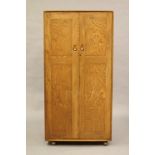 AN ERCOL ELM WINDSOR WARDROBE, mid 20th century, the two flush panel doors with oval wooden