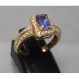 A TANZANITE AND DIAMOND DRESS RING, the oblong facet cut tanzanite claw set to a border of point set