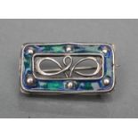 AN ARTS AND CRAFTS BROOCH, the open oblong panel with blue/green enamelling and plain bosses