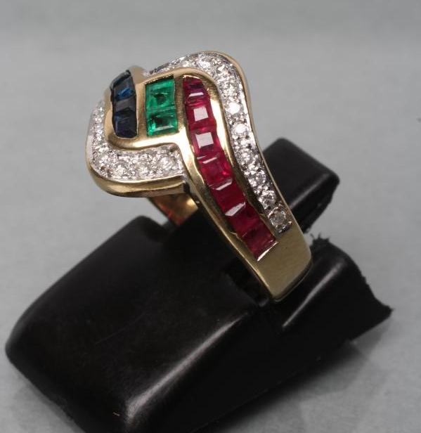 A RUBY, SAPPHIRE AND EMERALD DRESS RING. the channel set calibre cut stones within point set diamond - Image 2 of 3