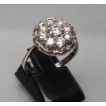 A NINE STONE DIAMOND CLUSTER RING, the round brilliants point and open set to a flower border and