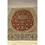 AN ISAFHAN CARPET, the claret red field with meandering flowering vines and centred by a pale blue