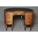 A LATE VICTORIAN DESK of kidney form, crossbanded with stringing, the moulded edged top lined in