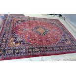 A PERSIAN CARPET, the claret field with floral sprays with navy and tangerine central gul and