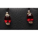 A PAIR OF GARNET AND DIAMOND EAR STUDS, the oval facet cut garnets bar set below a small diamond,