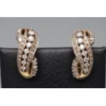 A PAIR OF DIAMOND EARRINGS, the open double "S" scroll panels set with graduated round brilliants
