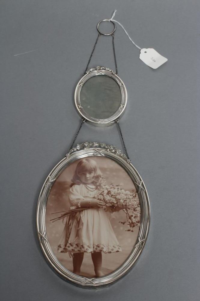 AN EDWARDIAN HANGING DOUBLE OVAL PHOTOGRAPH FRAME, maker William Comyns, London 1907, the reeded