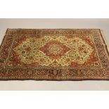 A PERSIAN RUG, the ivory serpentine field with central red gul and conforming spandrels all in