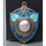 AN EDWARDIAN SILVER AND ENAMEL SECESSIONIST PENDANT, maker James Fenton, Birmingham 1909, the shield