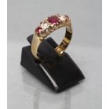 A FIVE STONE RUBY AND DIAMOND RING, the central facet cut ruby flanked by two old cut diamonds and