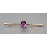 AN EDWARDIAN PROPELLOR BAR BROOCH centred by an oblong facet cut amethyst, stamped 9ct (Est. plus