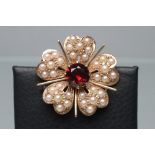 A LATE VICTORIAN 9CT GOLD FLOWERHEAD BROOCH, each of the five petals set with seven seed pearls with
