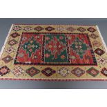 A FLAT WEAVE KILIM RUG, the red and green triple panel field each with a large gul and surround by a