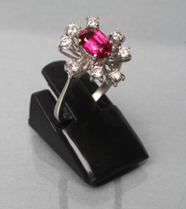 A RUBY AND DIAMOND DRESS RING, the oval facet cut ruby claw set to a star border of eight small