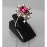 A RUBY AND DIAMOND DRESS RING, the oval facet cut ruby claw set to a star border of eight small
