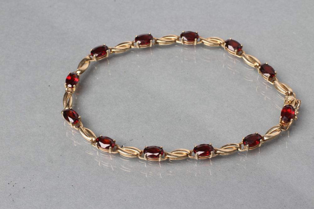 A GARNET BRACELET, the twelve oval facet cut stones claw set to a plain chain, stamped 375 (Est.