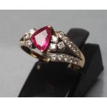 A RUBY AND DIAMOND RING, the triangular cut ruby claw set to diamond set asymmetric open shoulders