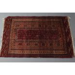 AN AFHGAN RUG in shades of red, blue and ivory, the narrow field with repeating geometric border,