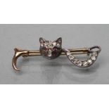 AN EDWARDIAN STOCK PIN, the crop centred by a fox mask with ruby cabochon eyes and diamond set