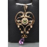 AN EDWARDIAN PENDANT/BROOCH, the open scroll shield set with seed pearls, centred by a peridot and