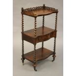 A VICTORIAN ROSEWOOD THREE TIER WHATNOT of oblong serpentine form with pierced gallery, spiral