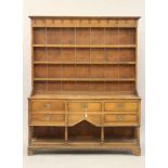 AN OAK DRESSER, early 19th century, the boarded delft rack with moulded cornice and frieze with iron