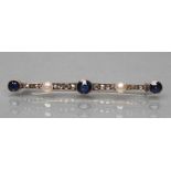 A SAPPHIRE AND DIAMOND BAR BROOCH, open back collet set with three circular sapphires, rose cut