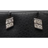 A PAIR OF DIAMOND EAR STUDS, the lozenge panels channel set with four small stones to white