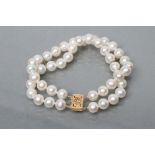 A TWO ROW CULTURED PEARL BRACELET with two fixed spacers between and foliate pierced clasp,