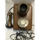 A GPO wall mounted telephone with wooden case and brass ear piece and dial. Case back size 24 x