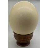 An Ostrich egg on a wooden holder.Condition ReportGood condition.