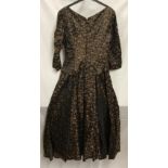 A 1950's cocktail dress by Chatil, black and brown silk style fabric with collared hips, v- neck,