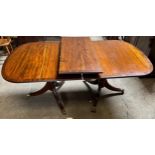 A 20thC mahogany twin pedestal dining table with extra leaf. Brass paw feet on brass castors. 180