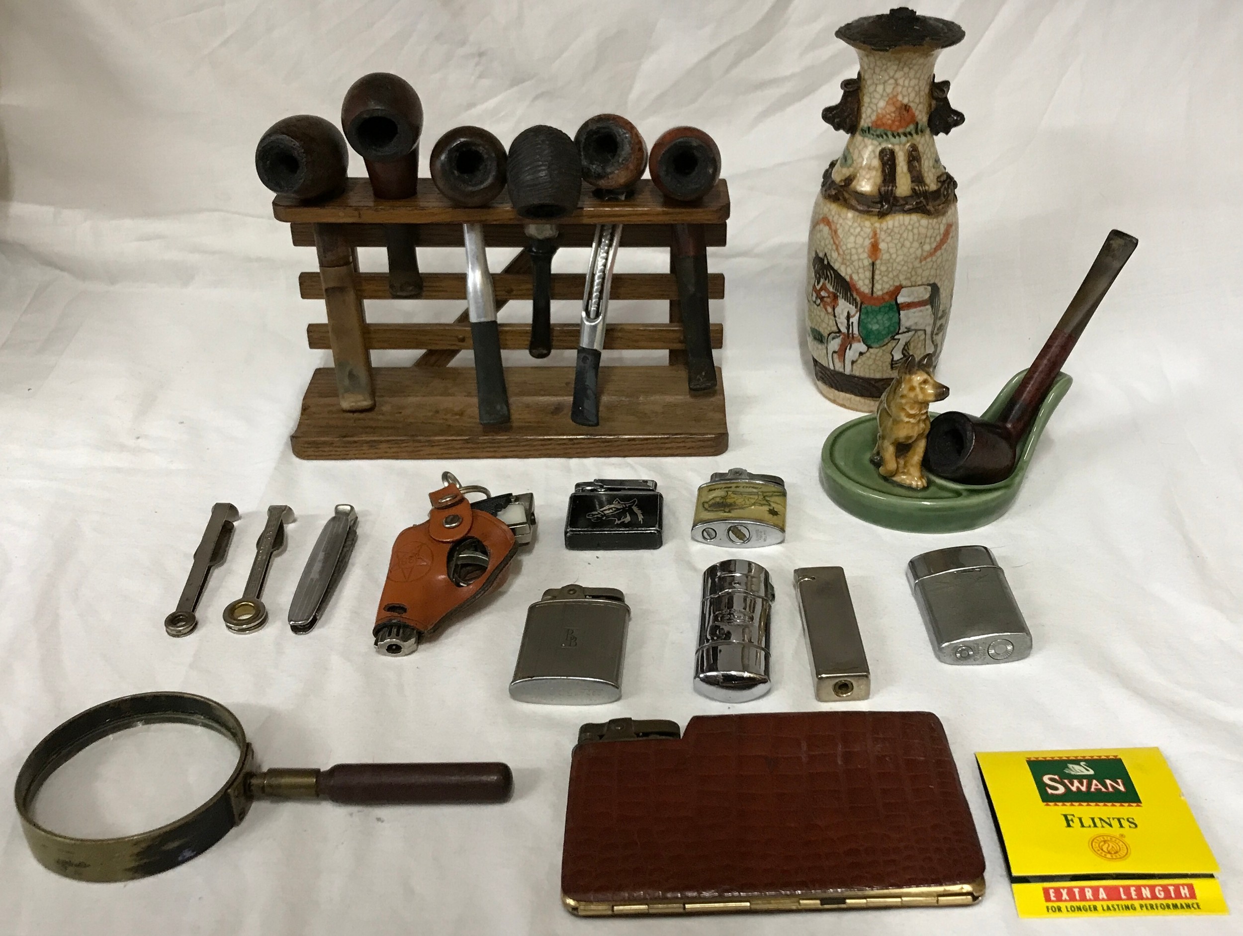 Smoking ephemera to include 7 pipes and rack, a Wade ceramic dog pipe holder, 8 lighters (various