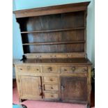 An oak dresser with raised back base with 3 drawers over 2 cupboards and 3 central drawers. Back