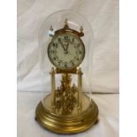 A Kundo clock in glass dome. Height to top of dome 22cm approx.Condition ReportChip to base of dome.