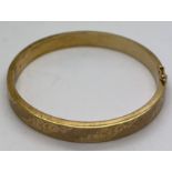 A 9ct gold hinged bangle with engraved decoration. 18gm.Condition ReportGood condition.